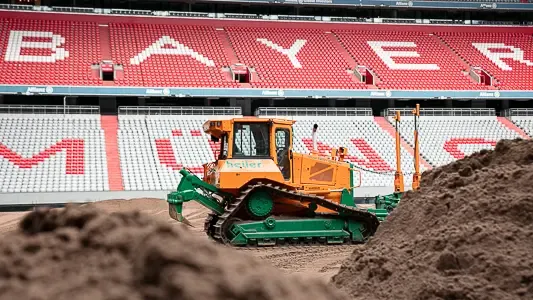 Eine Raupe von heiler installiert in der Allianz Arena des FC Bayern München eine neue Rasentragschicht.